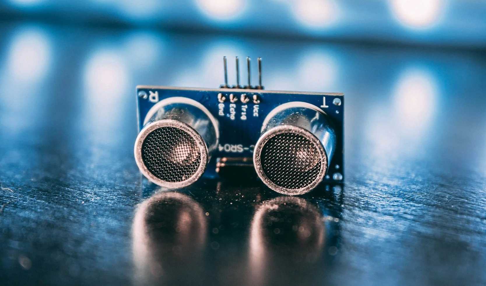 Ultrasonic sensor module on a dark reflective surface with blurred blue lights in the background